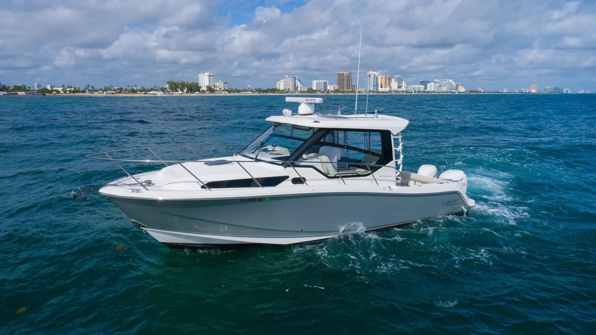 Boston Whaler 325 Conquest 2020 Boston Whaler 325 Conquest cruising on blue ocean near city skyline.