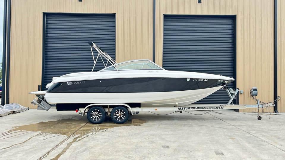 Cobalt 24SX 2005 Cobalt 24SX boat on trailer, parked outside a building with large doors.