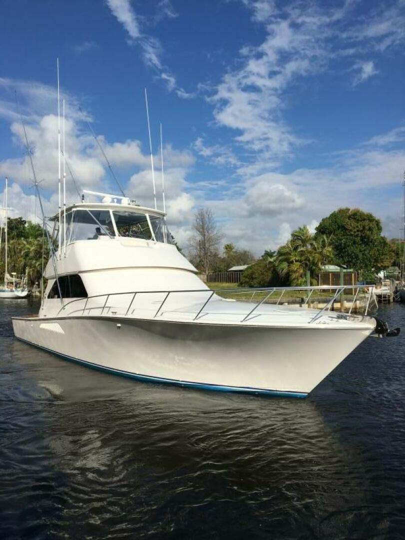 Viking 52 Convertible 2006 Viking 52 Convertible yacht on a sunny day, docked near lush greenery.