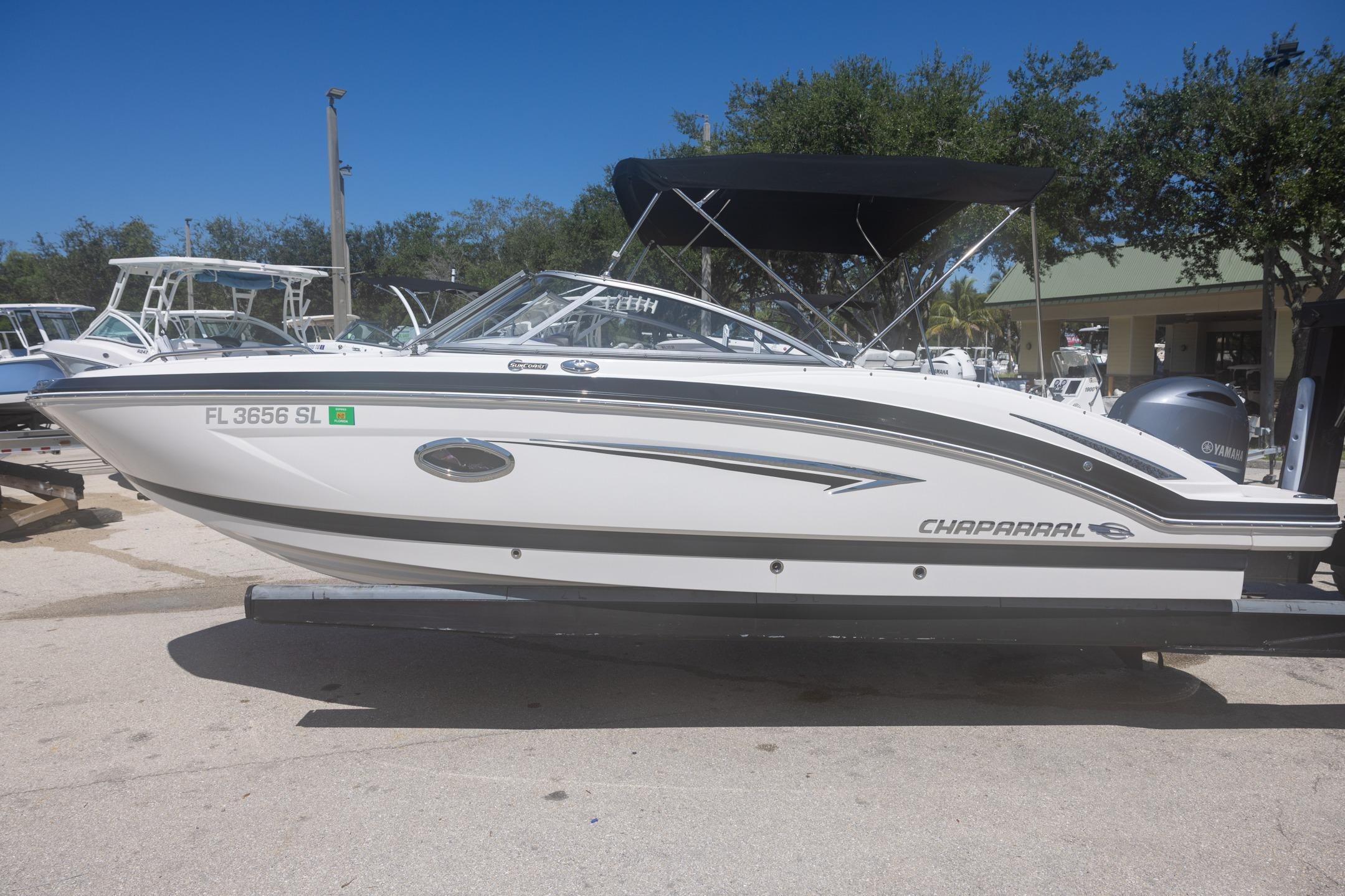 Chaparral 230 Suncoast 2019 Chaparral 230 Suncoast boat with black canopy, parked on a sunny day.