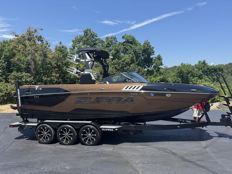 Supra 450 SE 2020 Supra 450 SE boat on trailer, parked outdoors with trees in background.