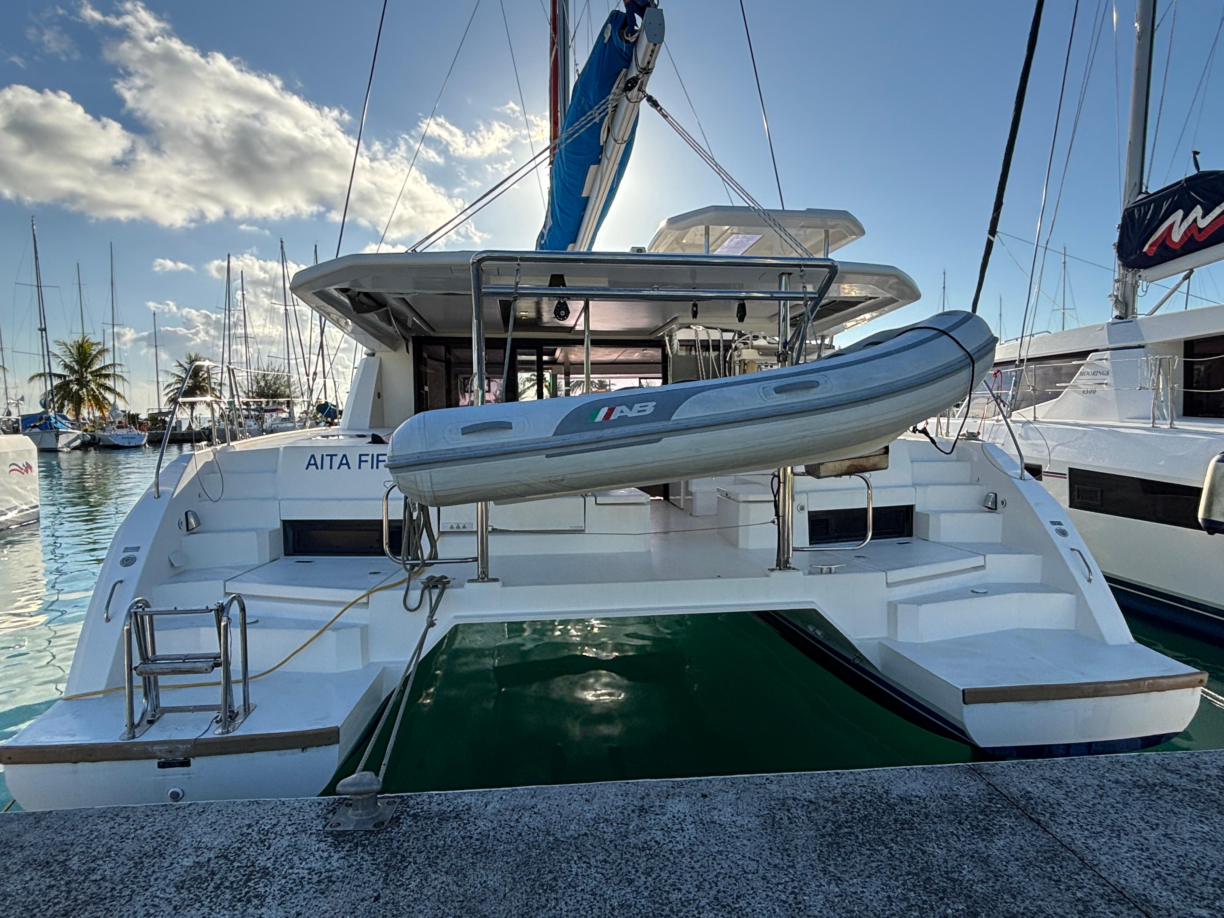 Leopard 45 2019 Leopard 45 catamaran docked with inflatable boat, under a clear blue sky.