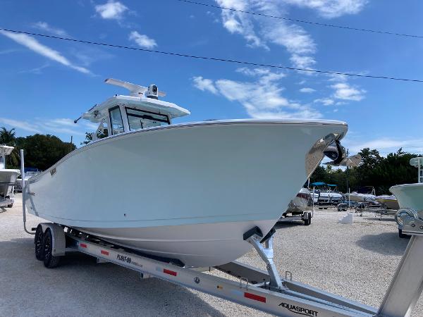 Aquasport 28 AS 2025 Aquasport 28AS boat on trailer under clear blue sky.