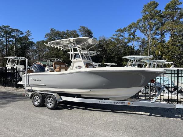 Pioneer 222 Sportfish 2025 Pioneer 222 Sportfish boat on trailer, parked outdoors, surrounded by trees and other boats.
