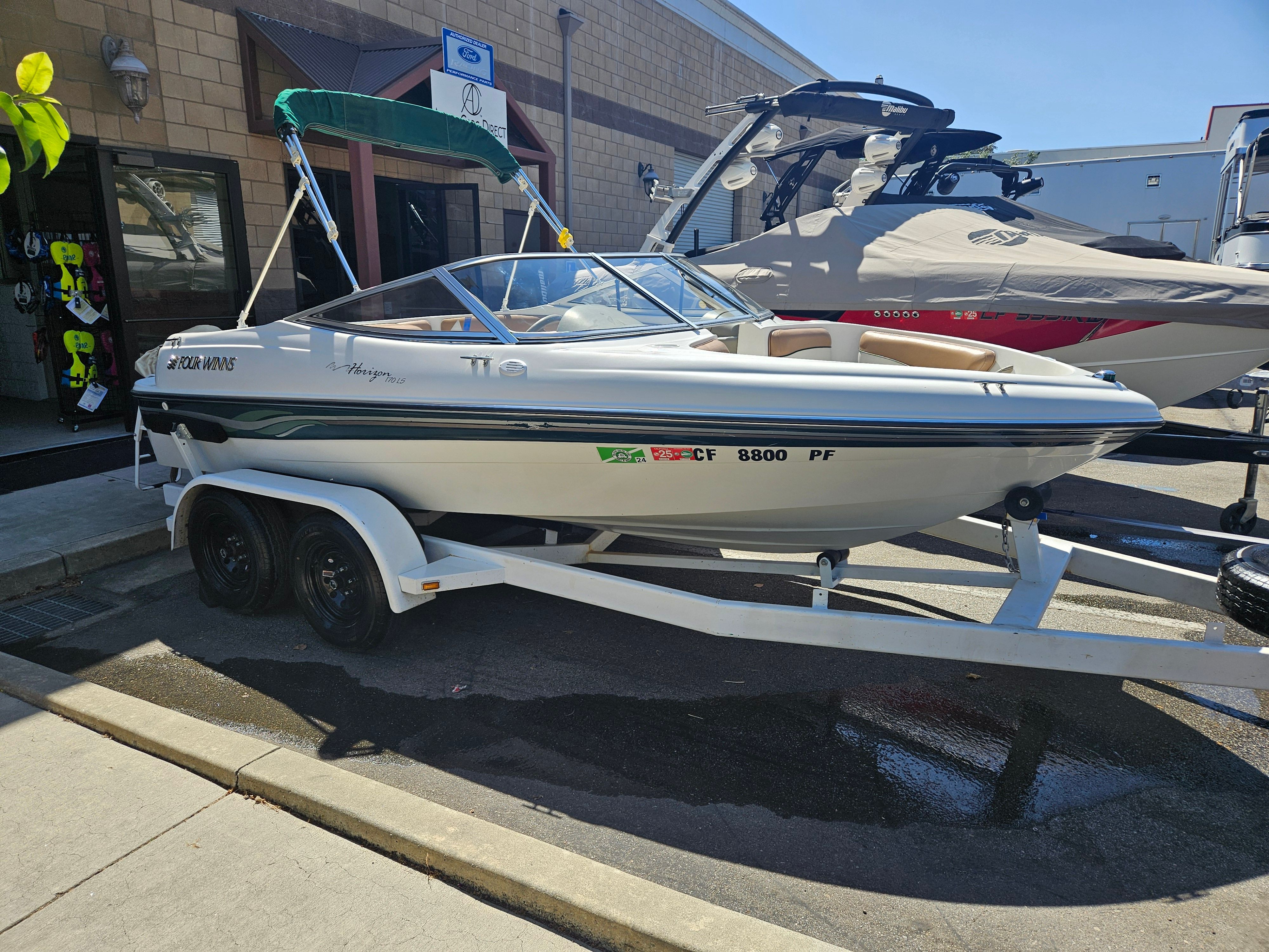 Four Winns 170 Horizon 1999 Four Winns Horizon 170 boat on trailer, parked outside a store.