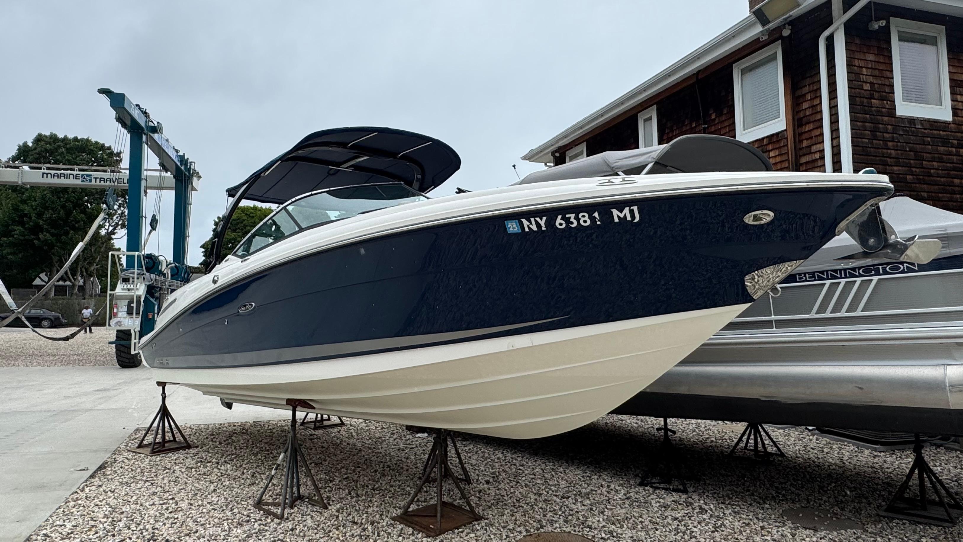 Sea Ray 270 SLX 2013 Sea Ray 270 SLX boat on stands, parked near a building and marine equipment.