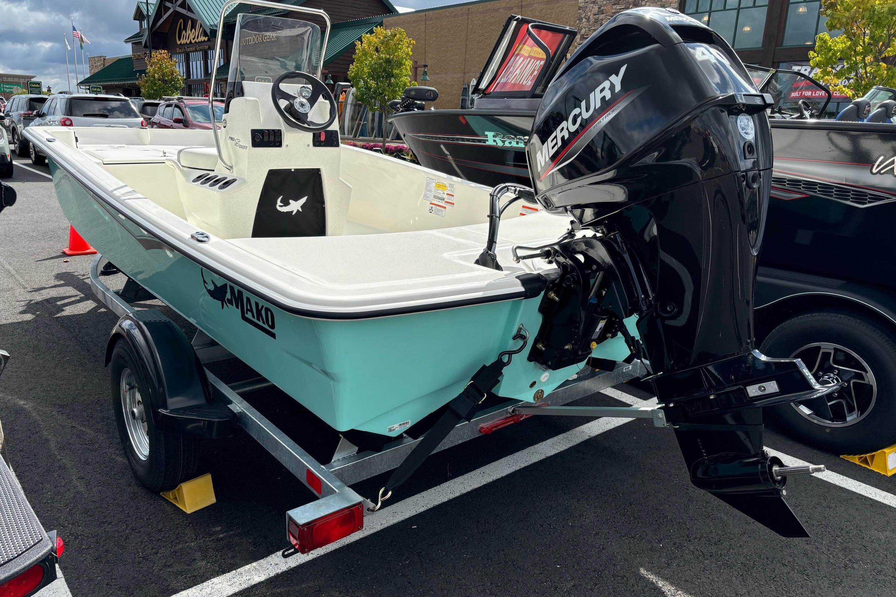 Mako Pro Skiff 15 CC 2025 Mako Pro Skiff 15 CC boat with Mercury engine on trailer in parking lot.