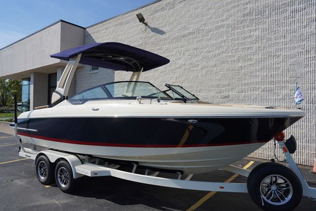 Chris-Craft Sportster 25 2025 Chris-Craft Sportster 25 boat on trailer, parked outdoors, with a sleek design and canopy.