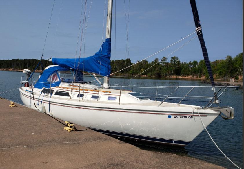Catalina 34 mkI 1988 Catalina 38 MKi sailboat docked by a serene lake with blue sail cover.