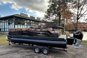 Regency 230 LE3 Sport 2025 Regency 230 LE3 Sport pontoon boat on trailer, parked near a modern building.