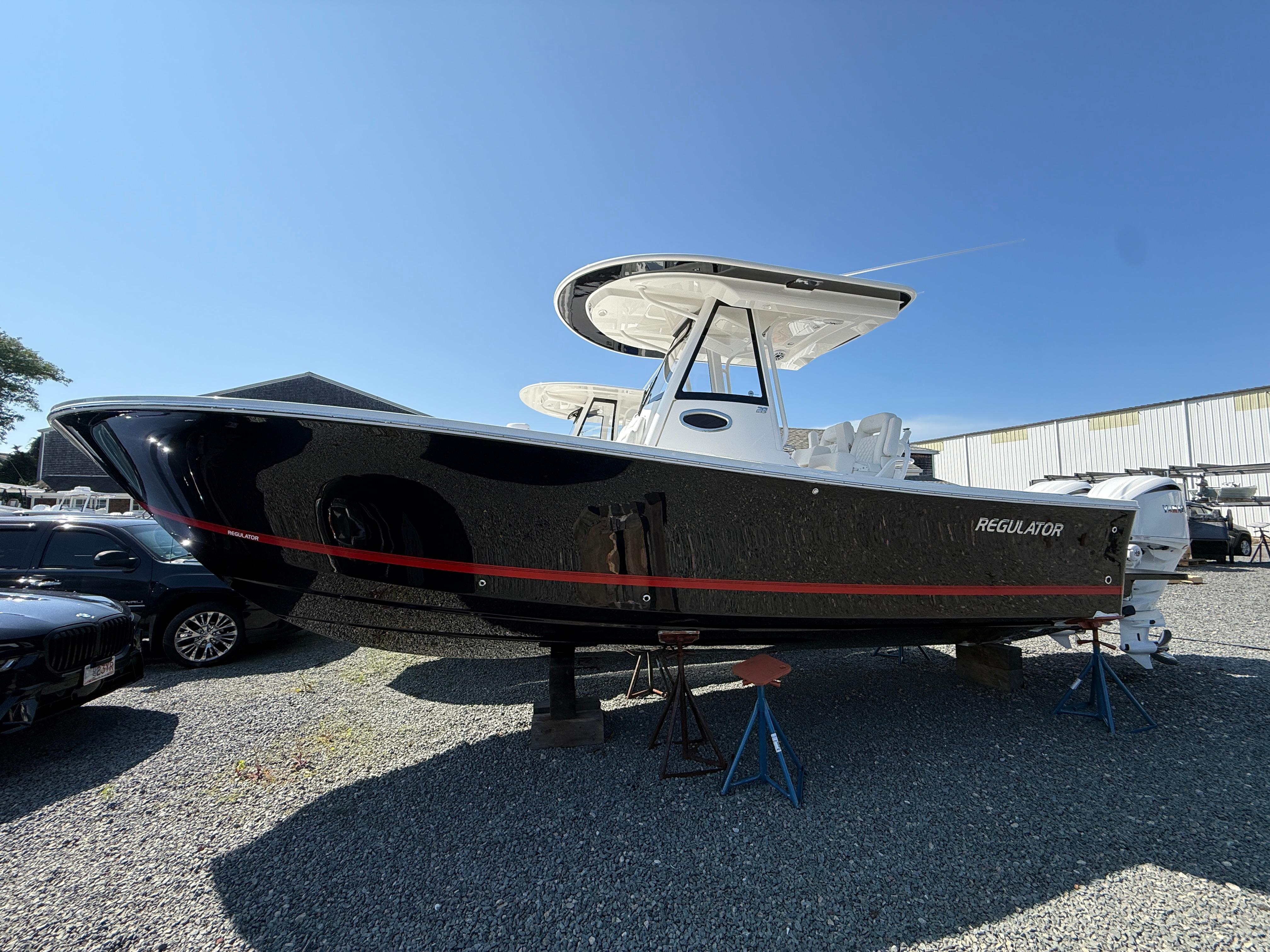 Regulator 28 2025 Regulator 28 boat with black hull and red stripe, displayed outdoors.