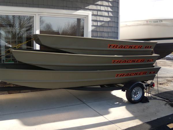 Tracker Grizzly 1436 Jon 2024 Tracker Grizzly 1436 Jon boats stacked on a trailer outside a building.