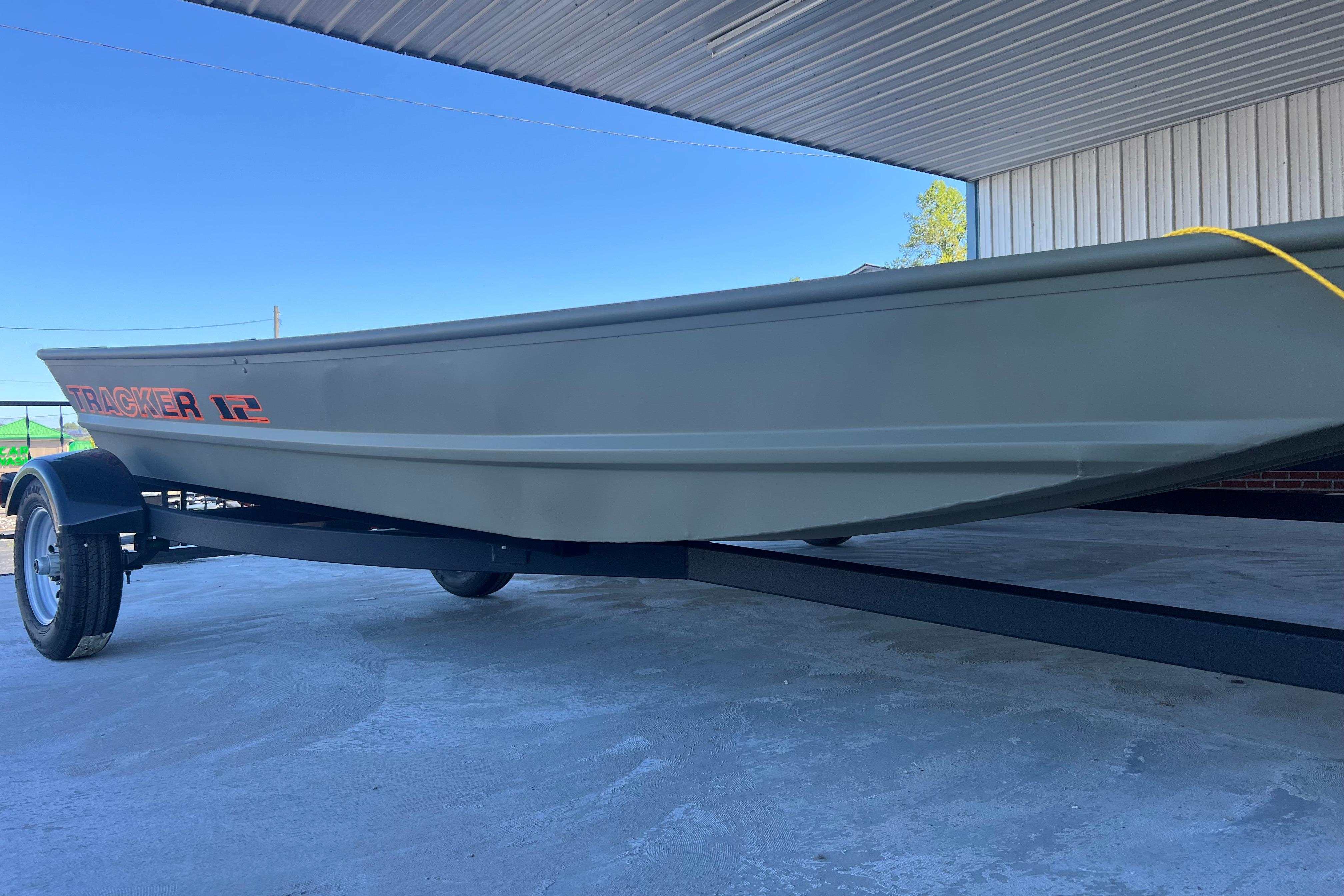 Tracker Grizzly 12 Jon 2026 Tracker Grizzly 12 Jon boat on trailer under a metal roof.