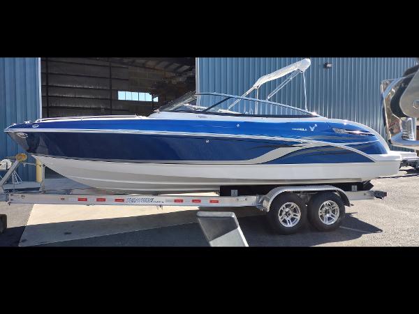 Formula 240 Bowrider 2024 Formula 240 BR boat on a trailer outside a blue warehouse.