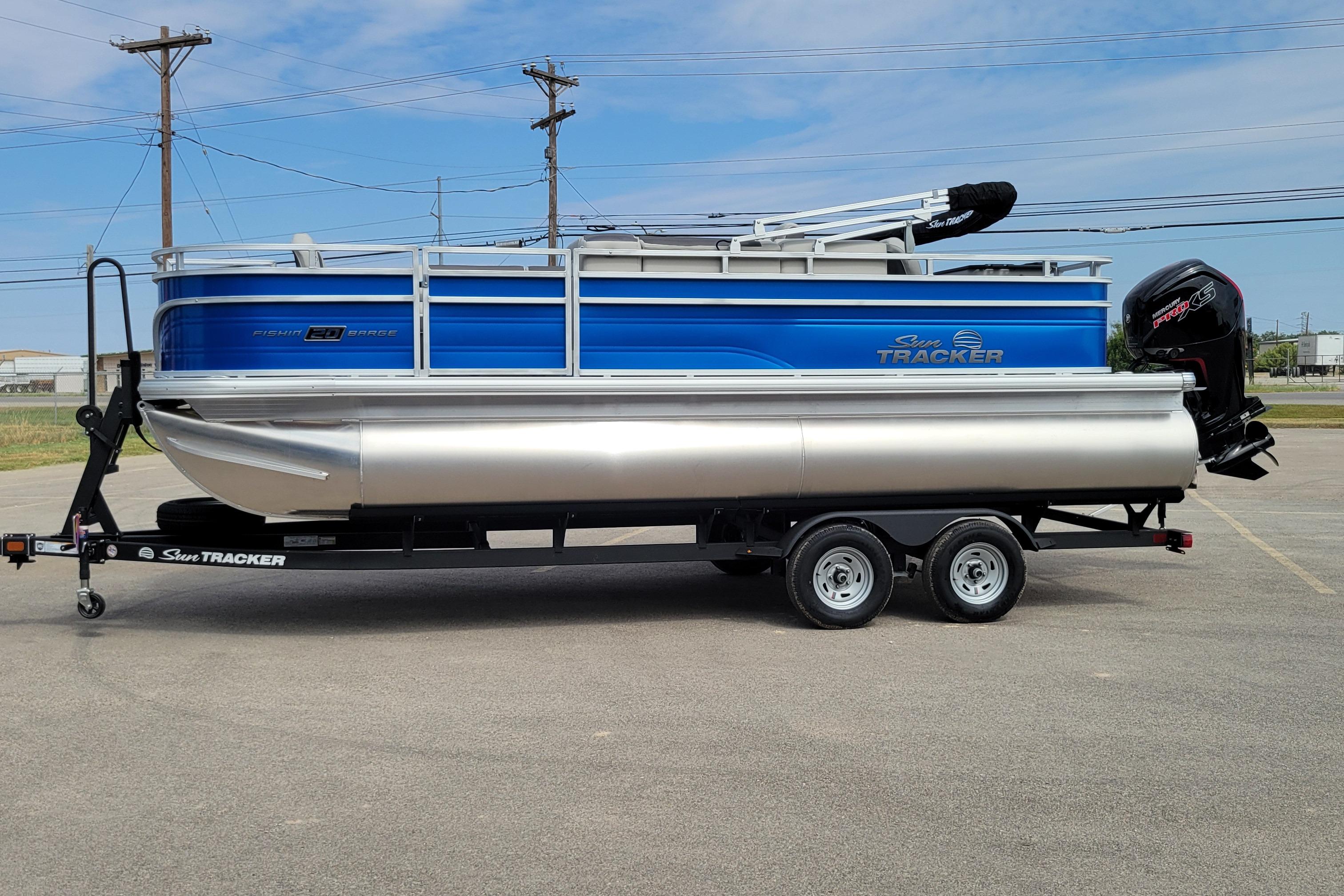 Sun Tracker Fishin' Barge 20 DLX 2026 Sun Tracker Fishin' Barge 20 DLX pontoon boat on trailer, blue and silver design.