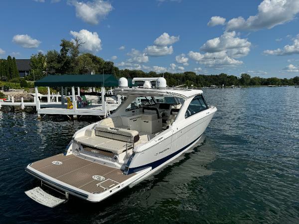 Regal LS36 2023 Regal LS36 boat docked on a serene lake under a partly cloudy sky.