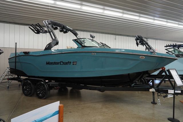 MasterCraft XT24 2025 MasterCraft XT24 boat in showroom, teal color, on trailer, under bright lighting.
