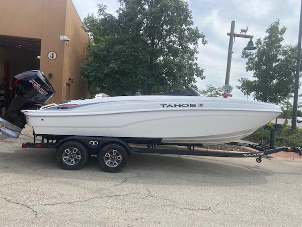 Tahoe T21 2025 Tahoe T21 boat on trailer, parked outdoors near trees and building.