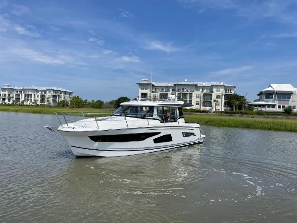 Jeanneau NC 1095 2024 Jeanneau NC 1095 boat cruising near waterfront homes.