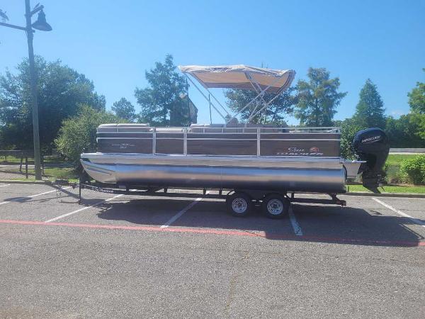Sun Tracker SportFish 22 DLX 2025 Sun Tracker SportFish 22 DLX pontoon boat on trailer in parking lot.