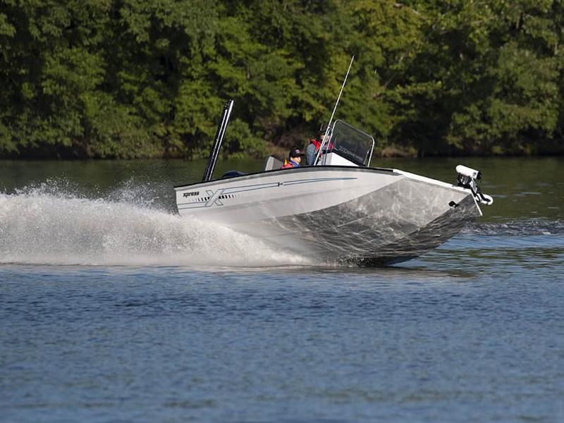 Xpress H210B 2026 Xpress H210B boat speeding on a lake with lush green trees in the background.