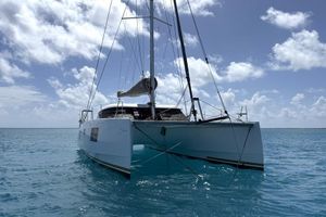 Nautitech 40 Open 2023 Nautitech 40 Open catamaran sailing on clear blue ocean under a partly cloudy sky.