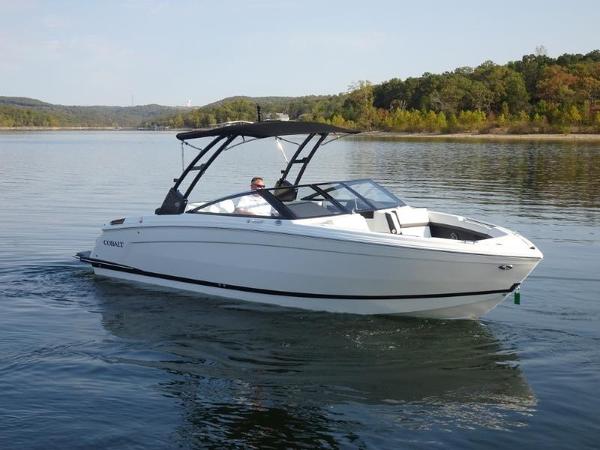 Cobalt R8 2025 Cobalt R8 boat cruising on a serene lake with lush green shoreline.