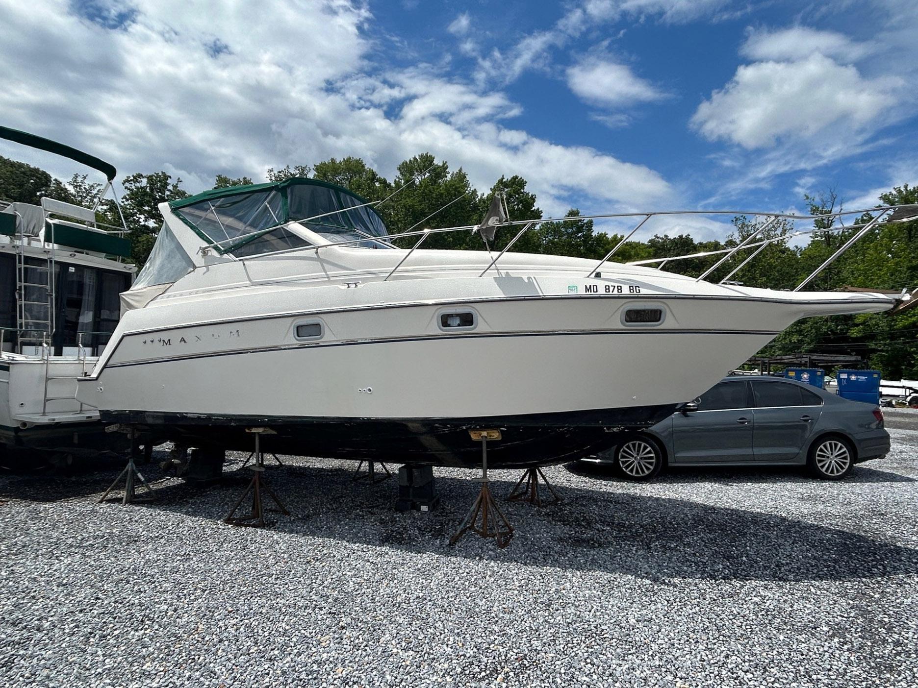 Maxum 2800 SCR 1998 Maxum 2800 SCR boat on stands, parked outdoors under a partly cloudy sky.