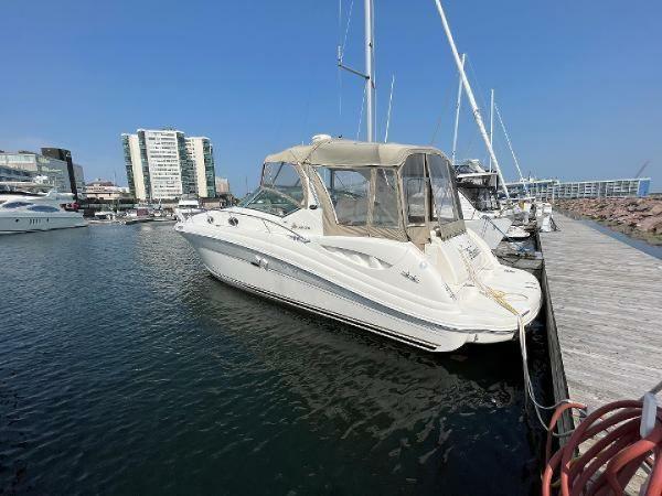 Sea Ray 340 Sundancer 2003 Sea Ray 340 Sundancer docked at marina, clear sky, modern buildings in background.