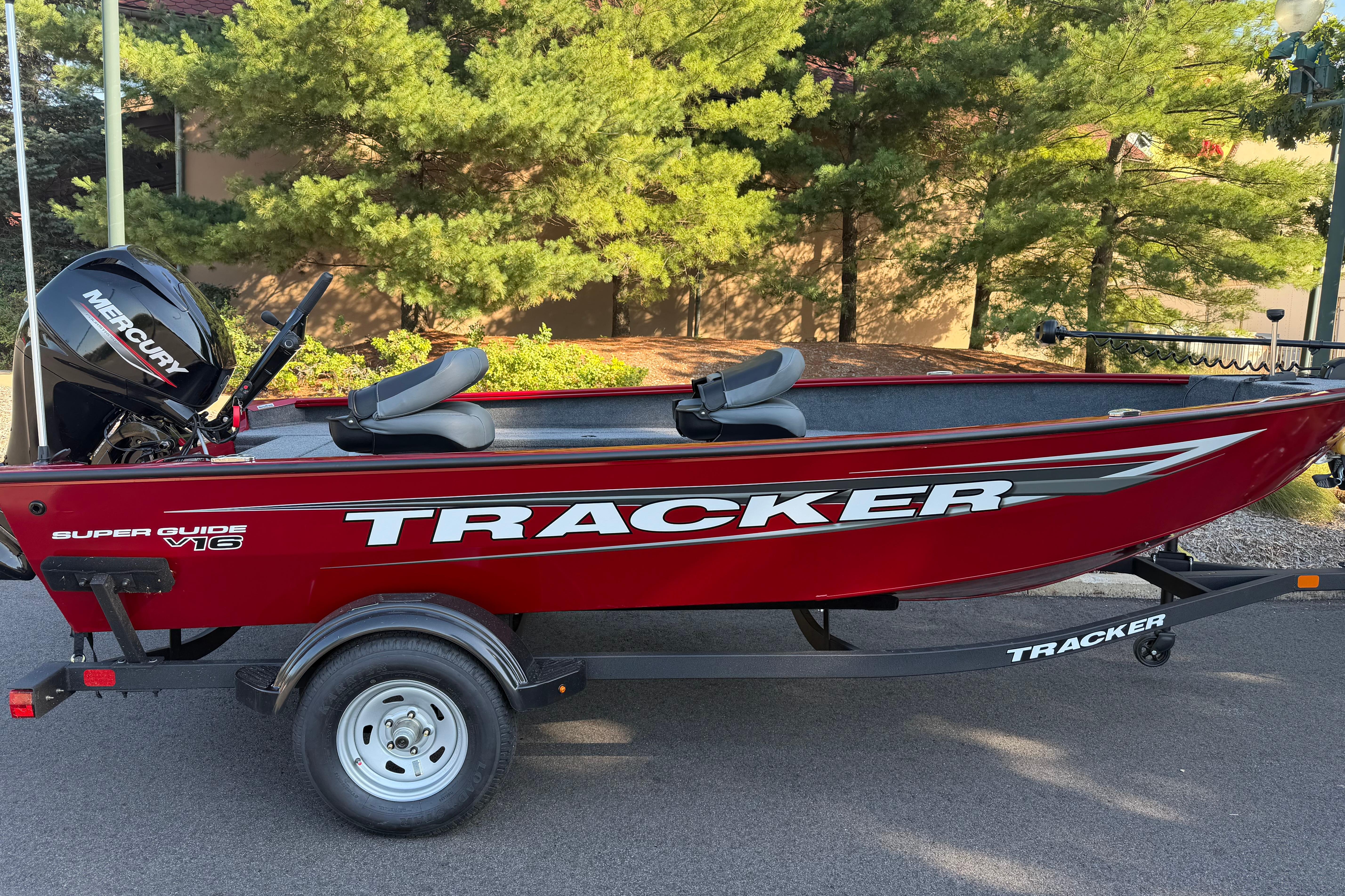 Tracker Super Guide V-16 T 2026 Tracker Super Guide V-16 T boat on trailer, red with Mercury engine, parked outdoors.