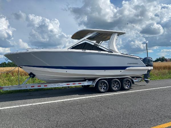 Chaparral 280 OSX 2025 Chaparral 280 OSX boat on trailer, parked on roadside under cloudy sky.