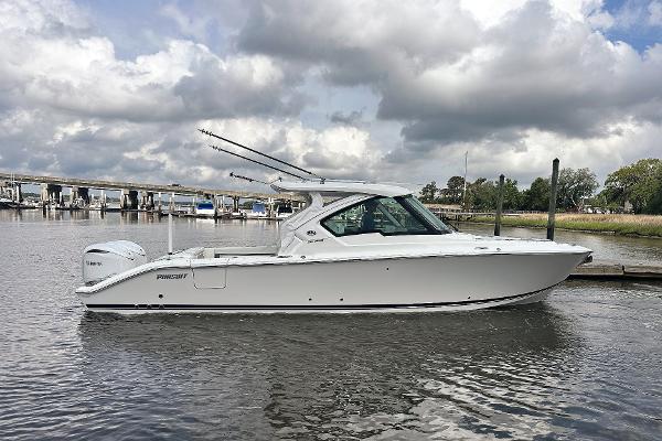 Pursuit DC 326 Dual Console 2025 Pursuit DC 326 Dual Console boat on a calm river under cloudy skies.