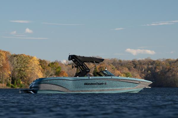 MasterCraft X24 2025 MasterCraft X24 boat on a serene lake with autumn foliage.