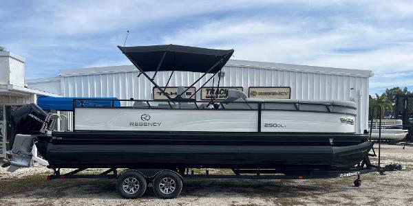 Regency 250 DL3 2023 Regency 250 DL3 pontoon boat on a trailer outside a dealership.