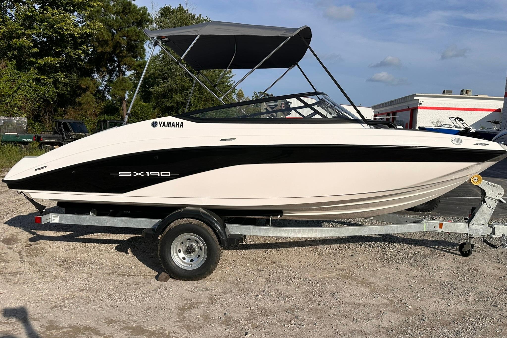 Yamaha Boats SX190 2025 Yamaha Boats SX190 on trailer, featuring sleek design and canopy, parked outdoors.