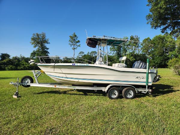 Key Largo 2000 CC 2005 Key Largo 210 CC boat on trailer, parked on grassy field.
