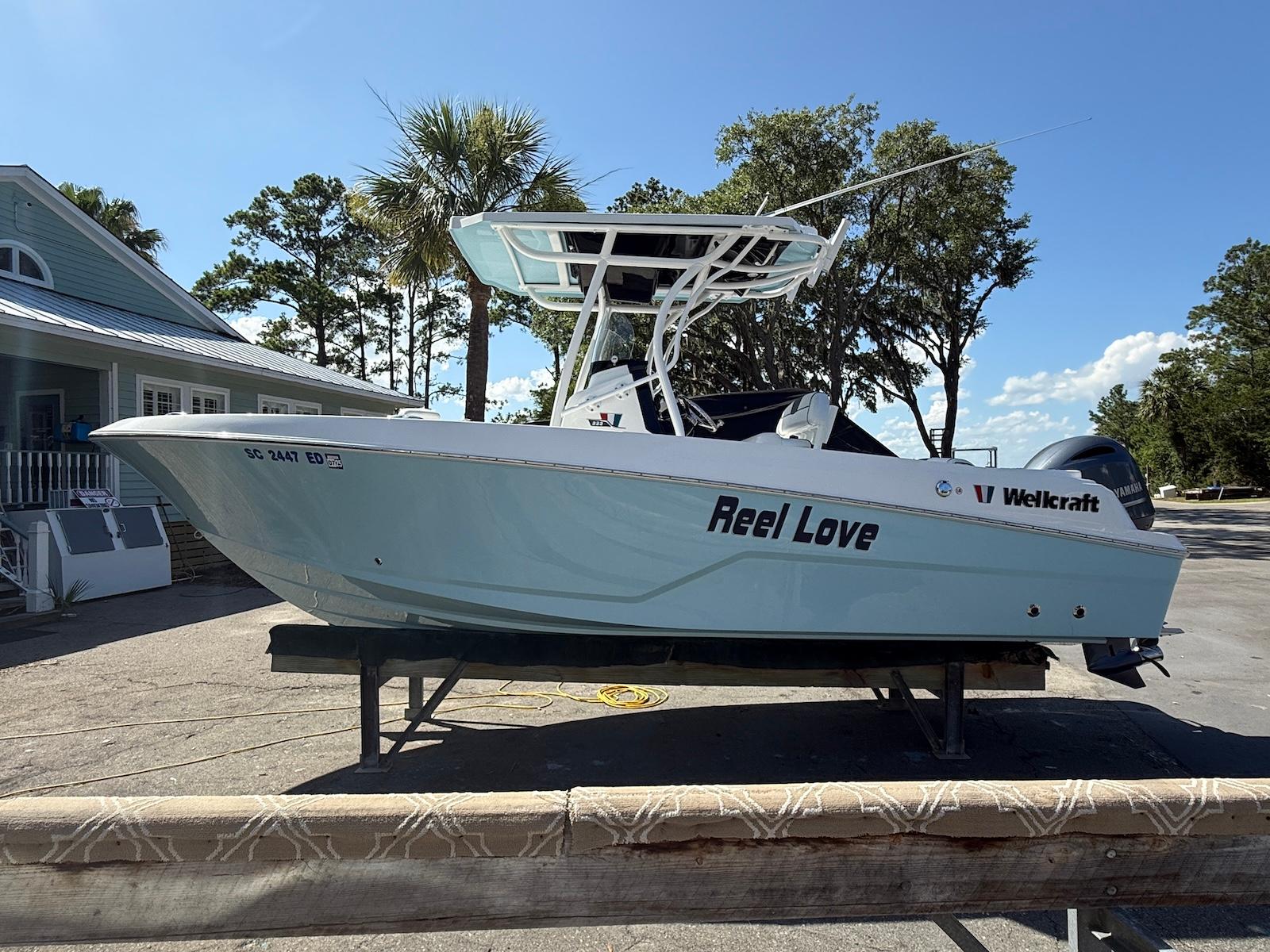 Wellcraft 222 Fisherman 2023 Wellcraft 222 Fisherman boat named "Reel Love" on a trailer, parked outdoors.
