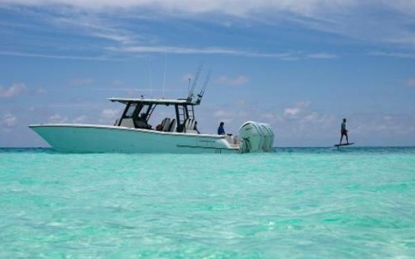 World Cat 400 CC-X World Cat 400CC-X boat on turquoise water, 2022 model, with person paddleboarding nearby.