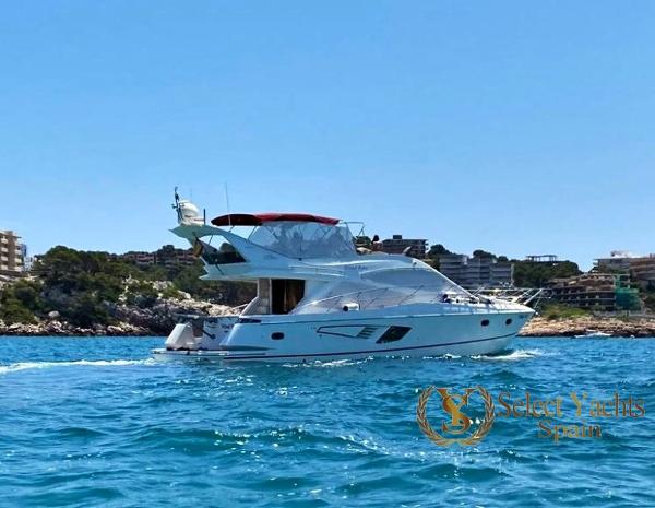 Galeon 530 Fly Galeon 530 Fly yacht cruising near rocky coastline, clear blue water, sunny day, 2009 model.