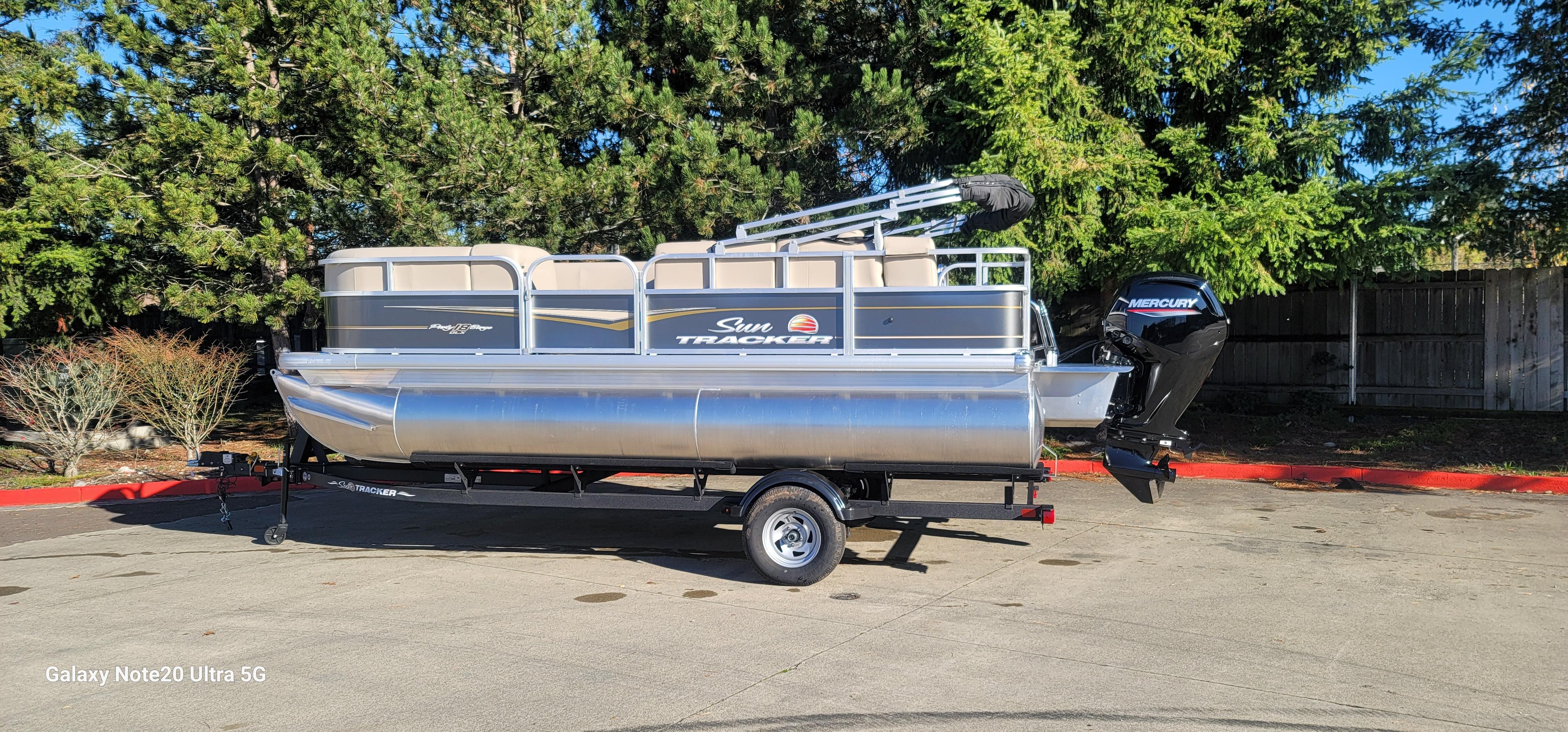 Sun Tracker Party Barge 18 DLX 2025 Sun Tracker Party Barge 18 DLX pontoon boat on trailer, parked outdoors.