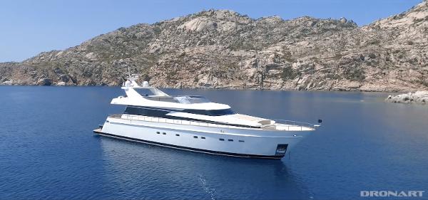 Cantieri di Pisa AKHIR 85 Luxury yacht Cantieri di Pisa AKHIR 85 (2007) cruising in serene blue waters near rocky coastline.