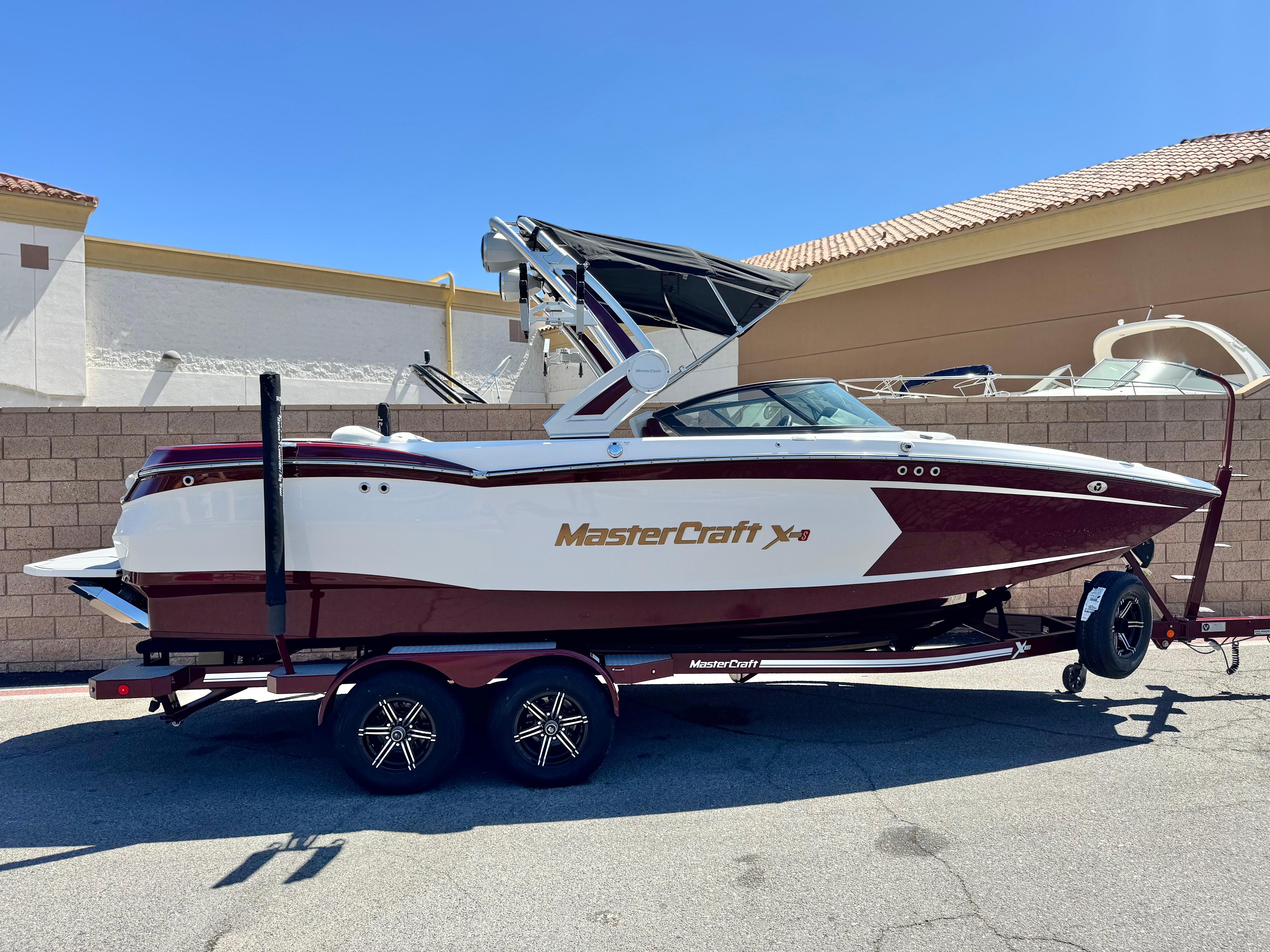 MasterCraft XStar S 2022 MasterCraft XStar S boat on trailer, parked outdoors, side view.
