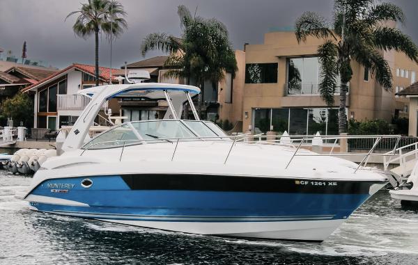 Monterey 355 Sport Yacht 2020 Monterey 355 Sport Yacht cruising near waterfront homes, featuring sleek blue and white design.