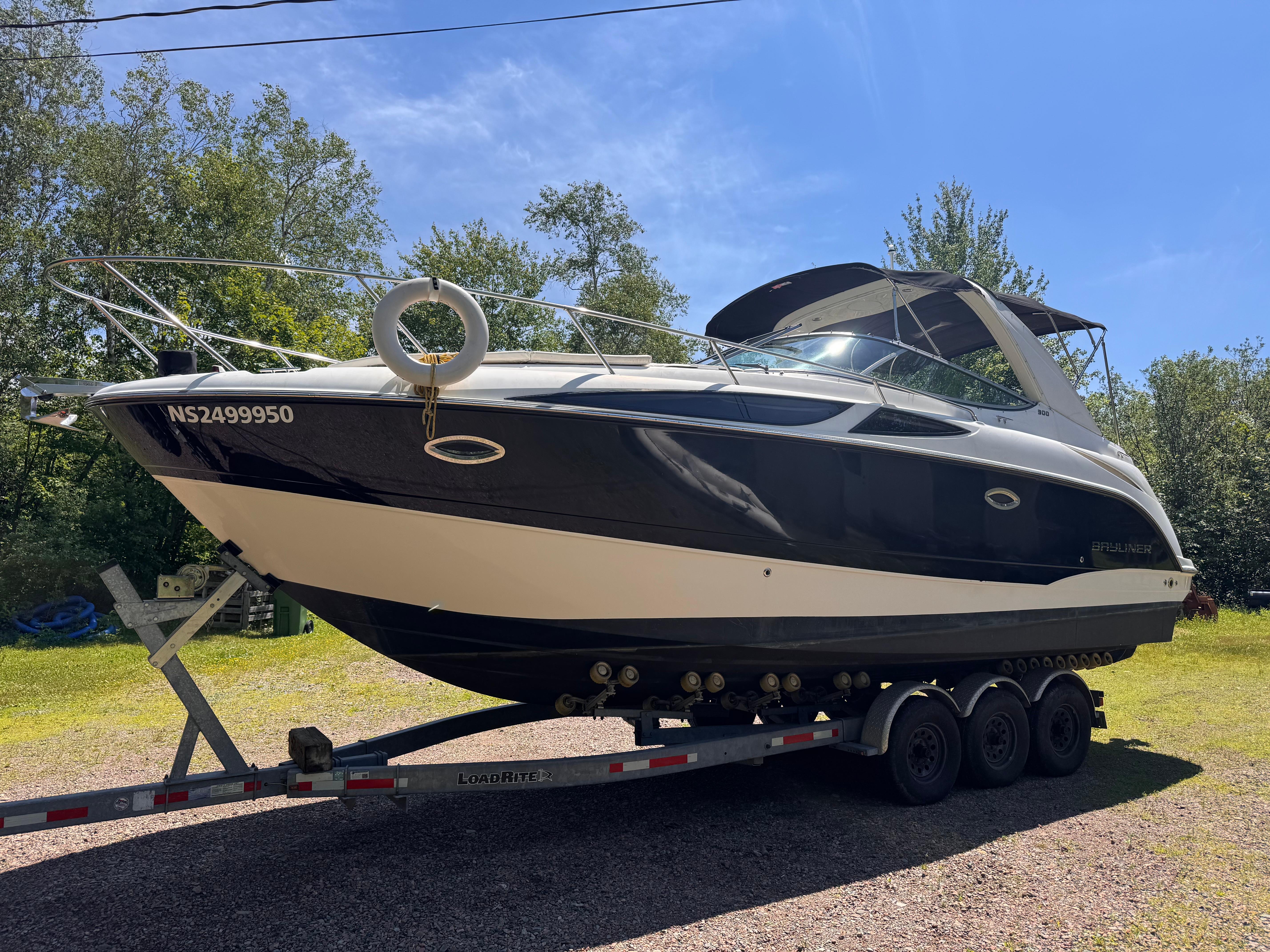 Bayliner 300 2009 Bayliner 300 boat on trailer, parked outdoors under clear sky.