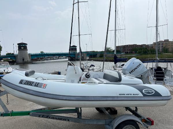 Walker Bay Generation 340 2023 Walker Bay Generation 340 boat on trailer by marina with sailboats.