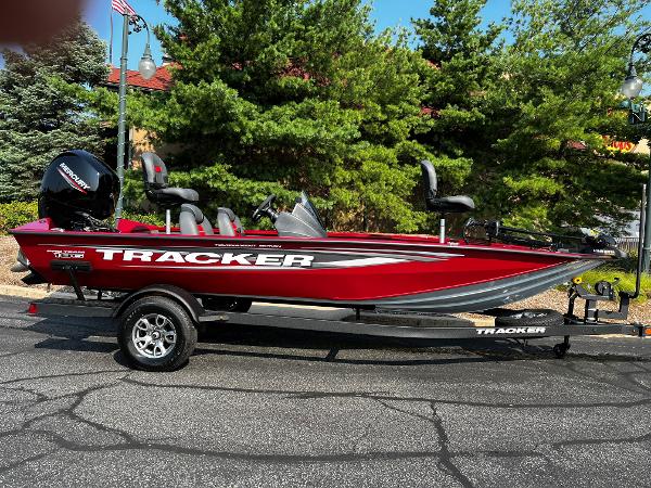 Tracker Pro Team 190 2025 Tracker Pro Team 190 boat, red, parked on a trailer, surrounded by trees.