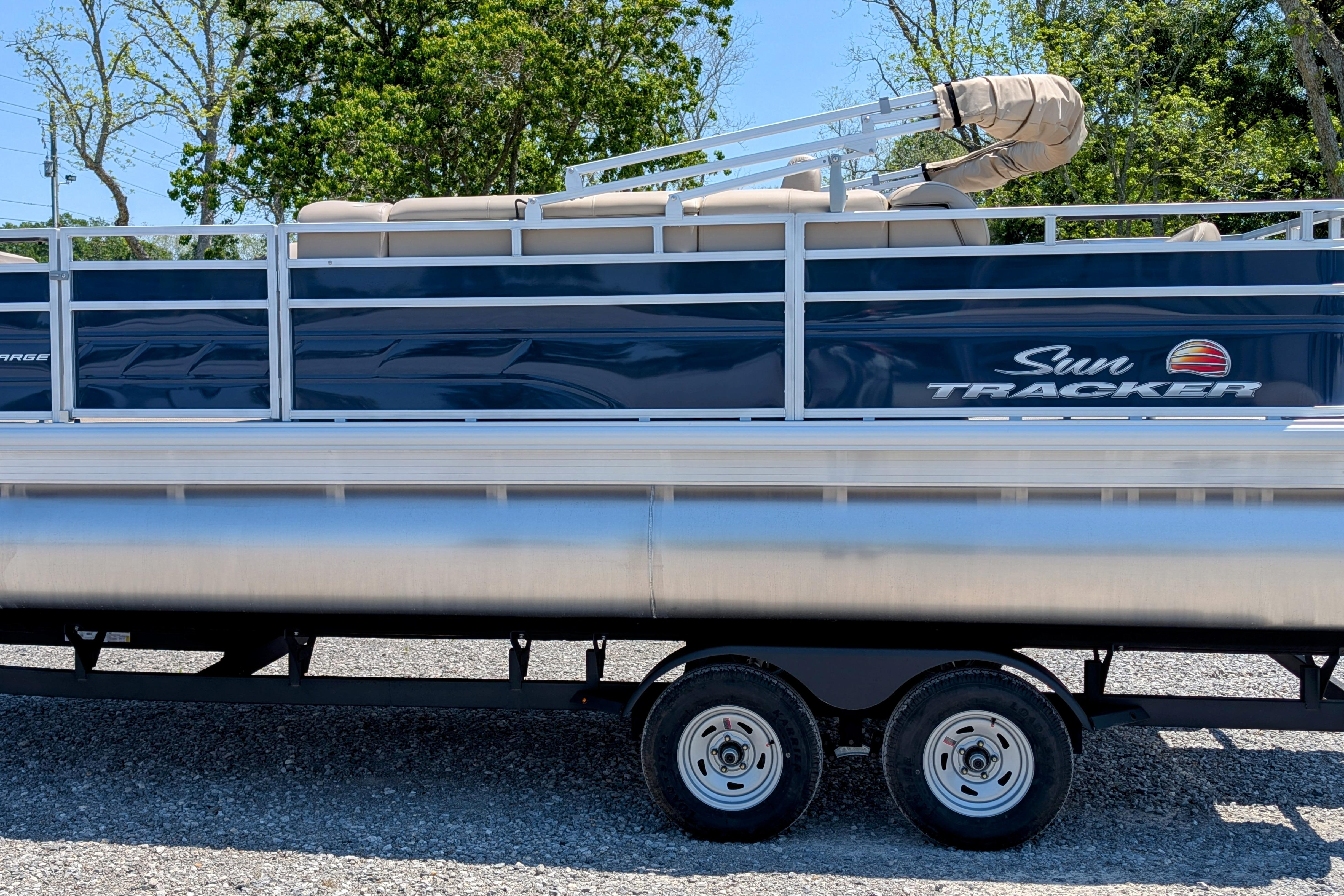 Sun Tracker Fishin' Barge 20 DLX 2025 Sun Tracker Fishin' Barge 20 DLX pontoon boat on trailer, side view.