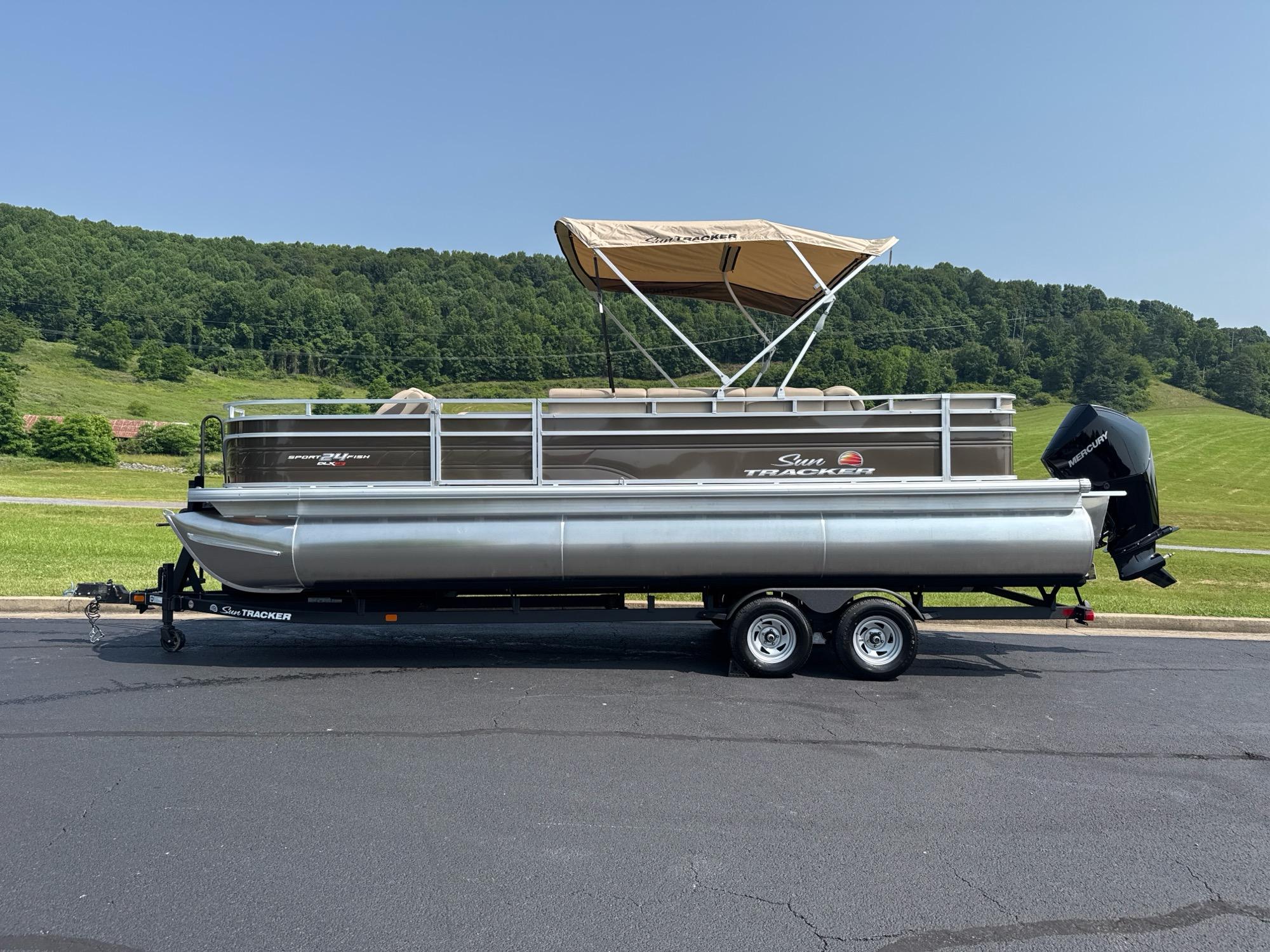 Sun Tracker Sportfish 24 XP3 2025 Sun Tracker Sportfish 24 XP3 pontoon boat on trailer, parked outdoors.