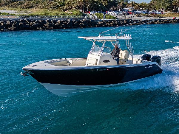 Cobia 296 Center Console 2013 Cobia 296 Center Console boat cruising on blue water near rocky shoreline.