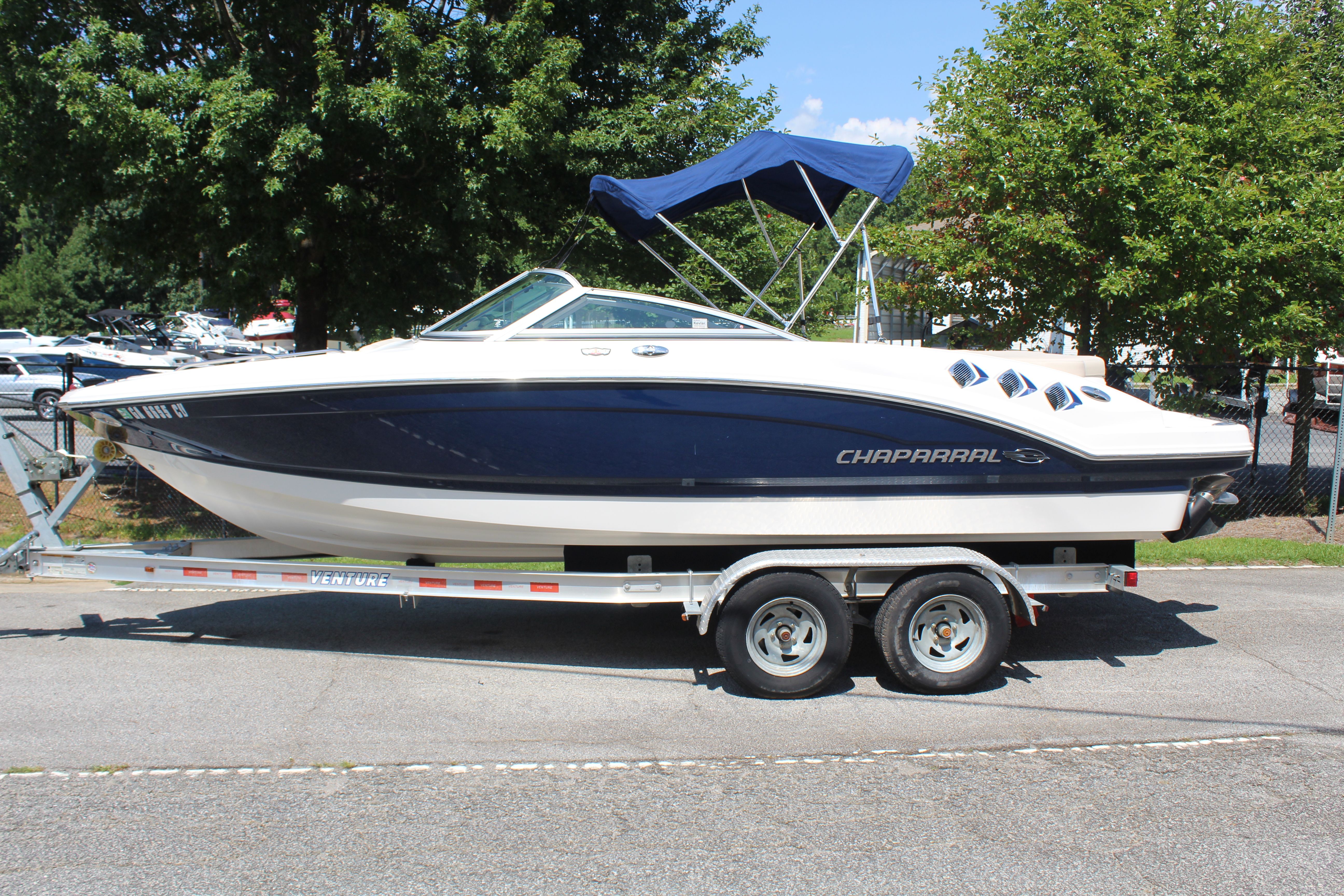 Chaparral 216 SSi 2011 Chaparral 216 SSi boat on trailer, blue and white, parked outdoors.